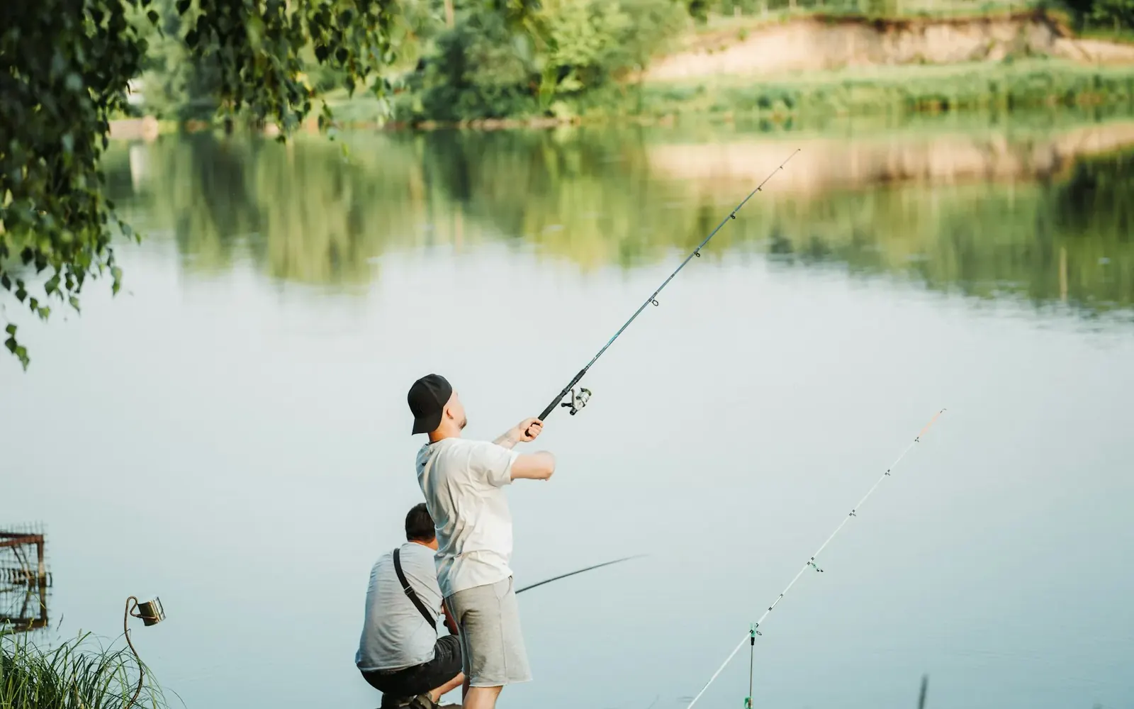 Pescador lanzando con caña desde la orilla de una laguna