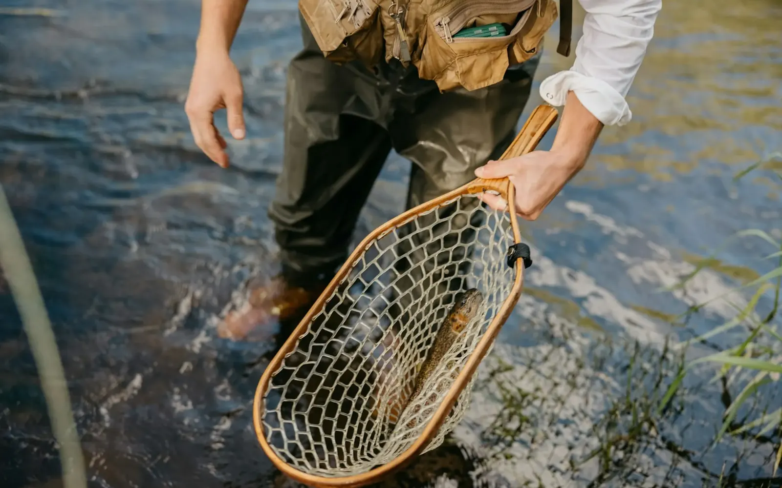 Pescador con un mediomundo de madera dentro del agua de un río