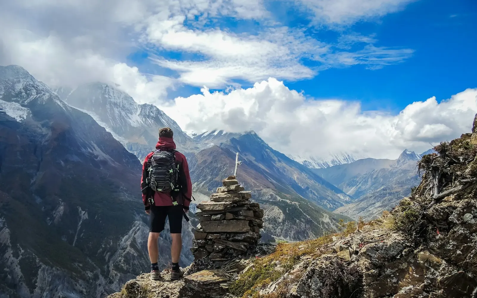 Persona de espaldas con mochila de trekking mirando un valle de montaña